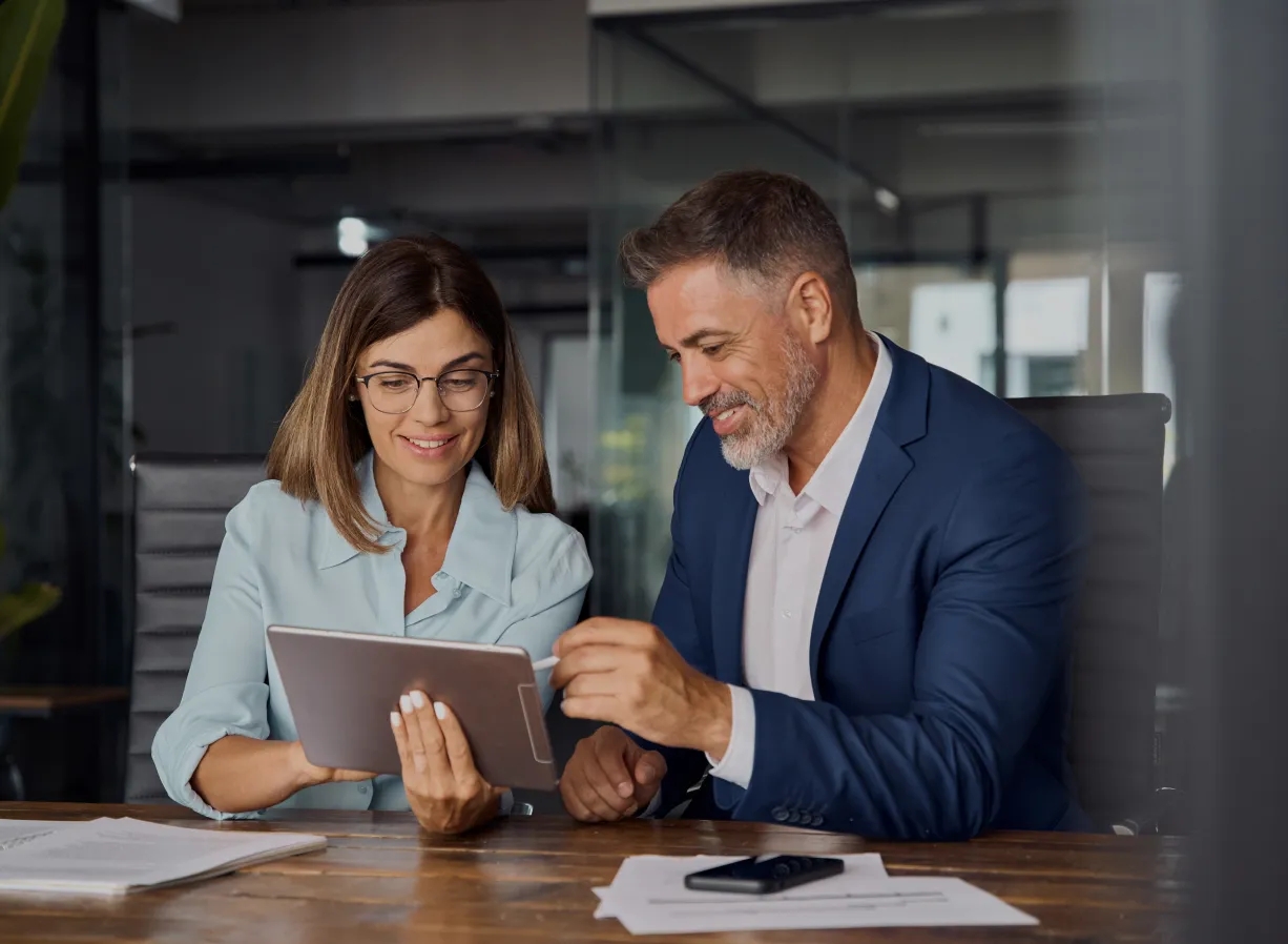 A man and woman in business attire looking at a tablet, discussing cloud studio client support