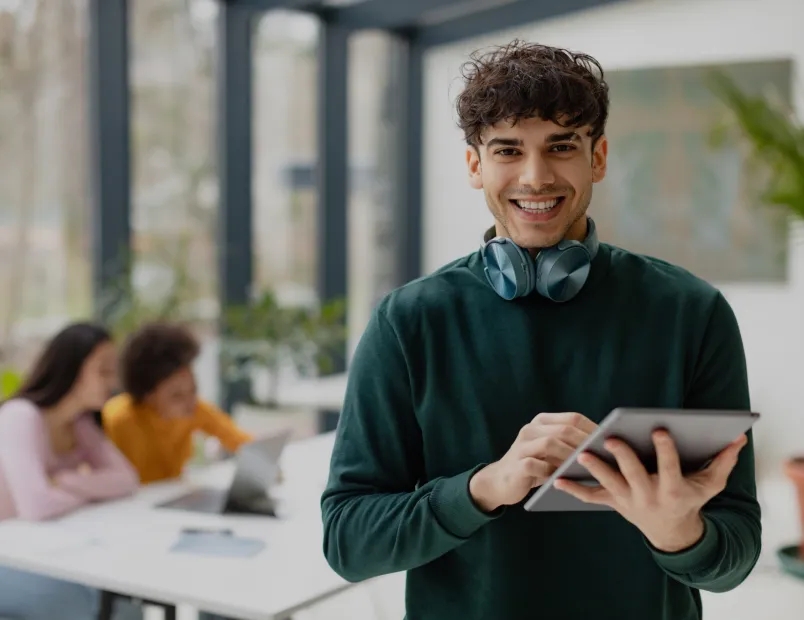 A man wearing headphones while holding a tablet.