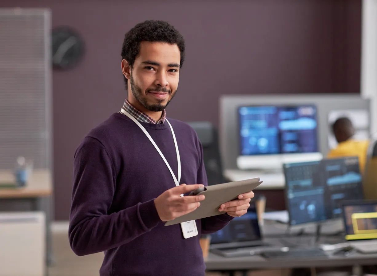 A man in a purple shirt works on cloud solutions platform engineering, holding a tablet