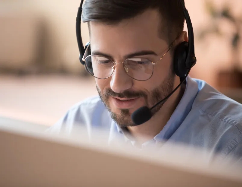 A man with glasses and a headset talking on the phone.