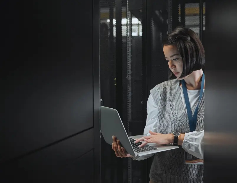 A woman in a white shirt focused on a computer screen, working on data integration with existing infrastructures