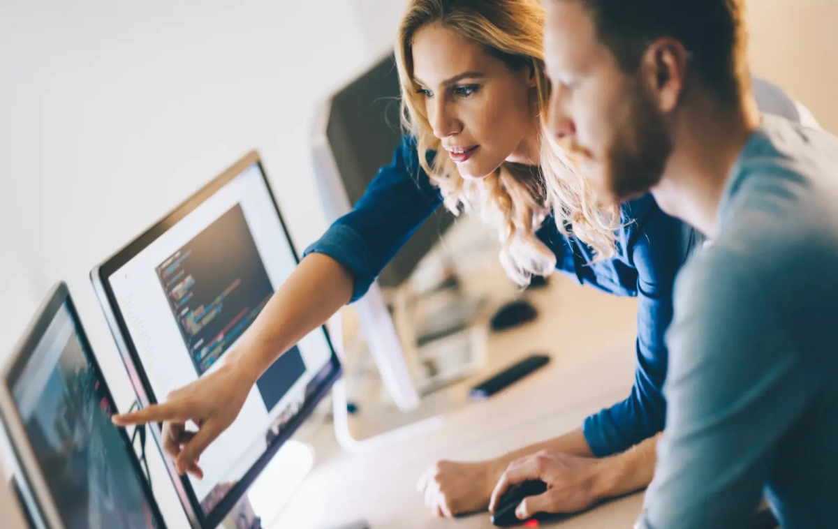 Two individuals collaborating on a computer screen, engaged in intelligent automation and RPA.