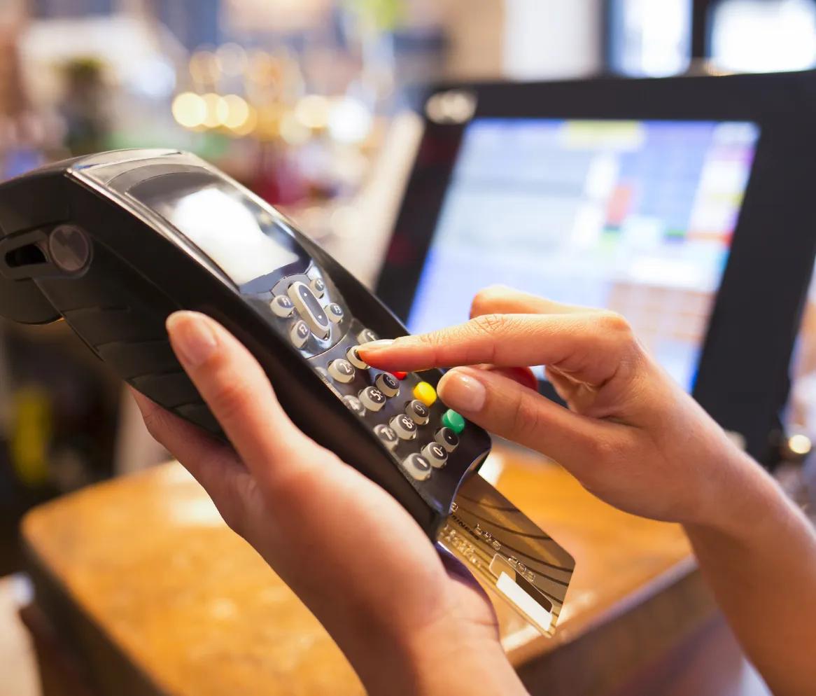 A woman making a purchase at a cash register using a credit card, highlighting the convenience of tech services for retail.