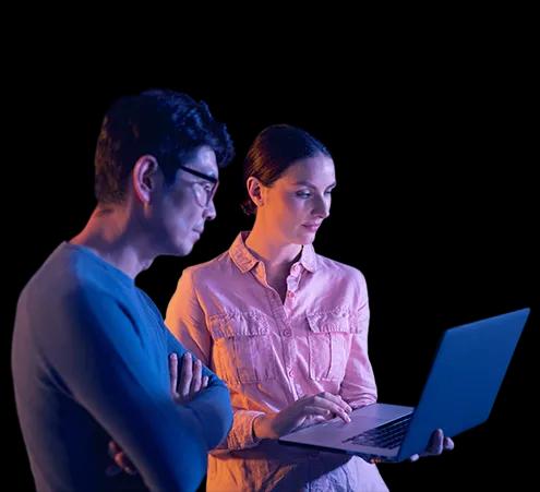 A man and woman engaged in a conversation about cloud migration while viewing a laptop