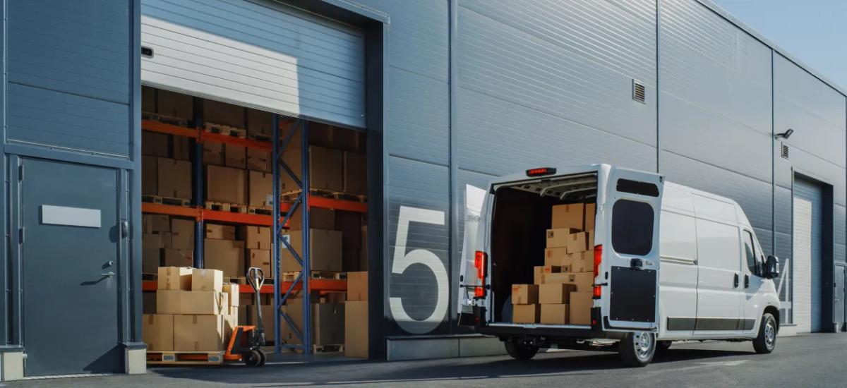 A white van parked at a warehouse, representing technology solutions for logistics and transportation.